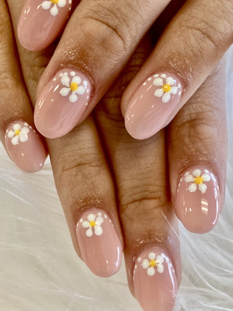 Nude pink almond nails with hand-painted white daisy art