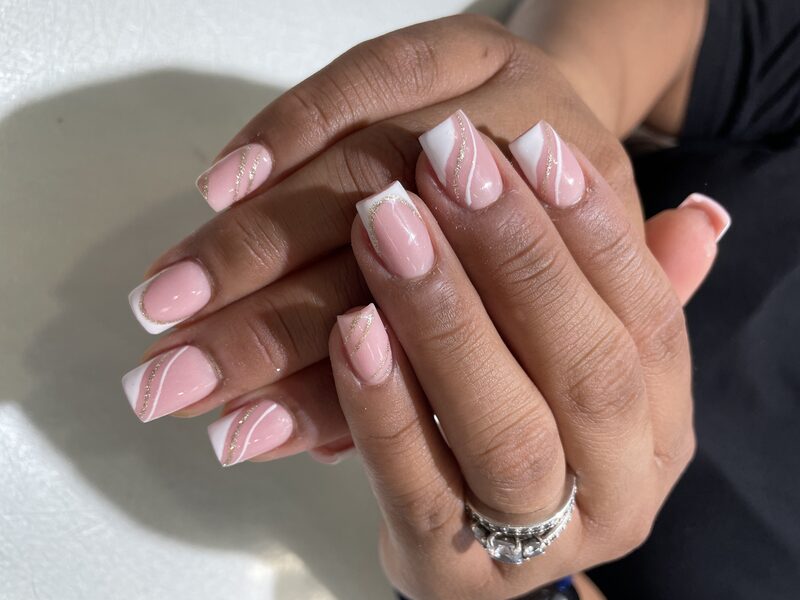 Nude pink nails with white french tips and gold-glitter swirl
